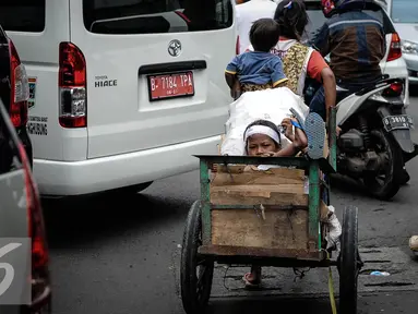 Seorang ibu membawa kedua anaknya mencari barang bekas dengan gerobak melintasi kawasan Wahid Hasyim, Jakarta, Kamis (6/10). Jumlah penduduk miskin di DKI Jakarta meningkat menjadi 384.300 orang atau 3,75% dari total penduduk. (Liputan6.com/Faizal Fanani)