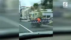 Seorang pria mengendarai motor sambil membawa 16 sepeda di China. Sepeda itu ia angkut menggunakan kayu yang diletakkan pada bahunya.
