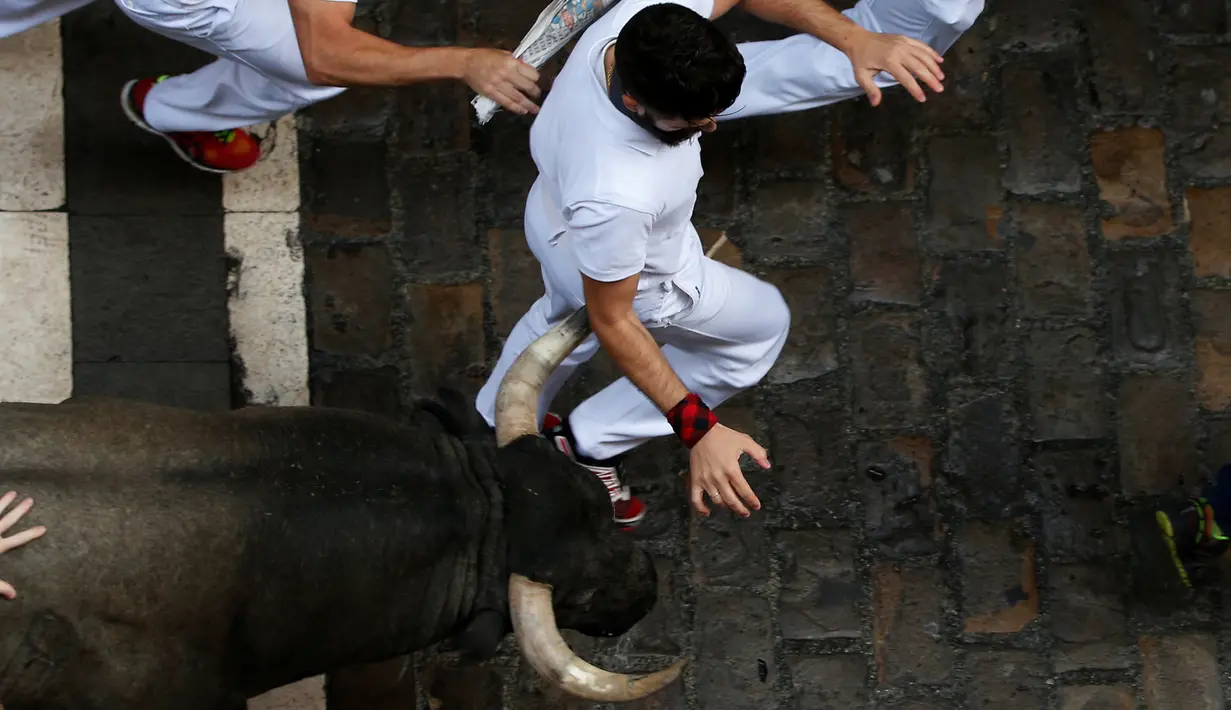 Seorang peserta terlihat menghindari serudukan banteng dalam festival San Fermin di Pamplona, Spanyol utara, (9/7). festival tahunan ini amat populer di Spanyol, dimana peserta diuji Keberaniannya dalam berhadapan dengan banteng. (REUTERS/Susana Vera)