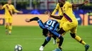 Striker Inter Milan, Lautaro Martinez, dijatuhkan bek Barcelona, Samuel Umtiti,  pada laga Liga Champions di Stadion San Siro, Milan, Selasa (10/12). Inter kalah 1-2 dari Barcelona. (AFP/Isabella Bonotto)
