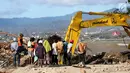 Warga menyaksikan proses evakuasi Nanang Kosim (20) menggunakan alat berat, yang diduga masih tertimbun di dalam tanah pascagempa dan tsunami Palu di Pantai Talise, Sulawesi Tengah, Senin (8/10). (Liputan6.com/Fery Pradolo)