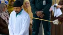 Mereka dicambuk masing-masing 6 kali setelah tertangkap sedang bermain judi batu domino. (CHAIDEER MAHYUDDIN / AFP)