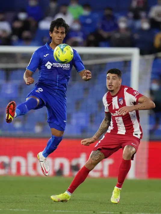 Penyerang Getafe, Jose Juan Macias (kiri) berebut bola dengan bek Atletico Madrid, Jose Gimenez pada laga pekan keenam Liga Spanyol di Stadion Coliseum Alfonso Perez, Rabu (22/9/2021) dini hari WIB. Luis Suarez memborong dua gol saat Atletico Madrid mengalahkan Getafe 2-1. (AP Photo/Manu Fernandez)