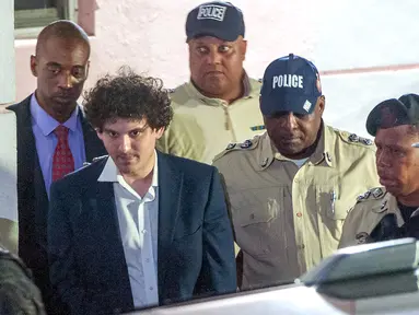 Pendiri FTX Sam Bankman-Fried (tengah) dibawa pergi dengan tangan diborgol oleh petugas Kepolisian Kerajaan Bahama di Nassau, Bahamas, 13 Desember 2022. Kantor Kejaksaan Agung Bahama mengumumkan bahwa  Sam Bankman-Fried telah ditangkap dan kemungkinan akan diekstradisi dalam waktu singkat kembali ke Amerika Serikat untuk diadili. (Mario Duncanson/AFP)