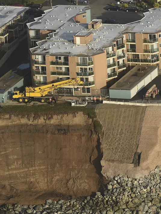 Pekerja merenovasi bangunan apartemen di atas bukit yang terkikis akibat badai El Nino di Pacifica Apartemen di Pacifica, California (26/1). Tiga Kompleks apartemen dikota ini  telah mengalami erosi akibat badai El Nino. (REUTERS/Noah Berger)