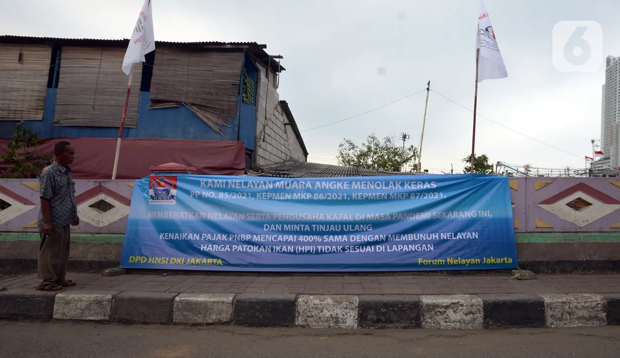 Warga melihat spanduk penolakan PP Nomor 85 Tahun 2021 KKP terkait tarif atas jenis PNBP di Pelabuhan Muara Angke, Jakarta, Sabtu (9/10/2021). Ratusan nelayan memilih tidak melaut untuk memprotes terbitnya PP Nomor 85 Tahun 2021 KKP terkait tarif atas jenis PNBP. (merdeka.com/Imam Buhori)