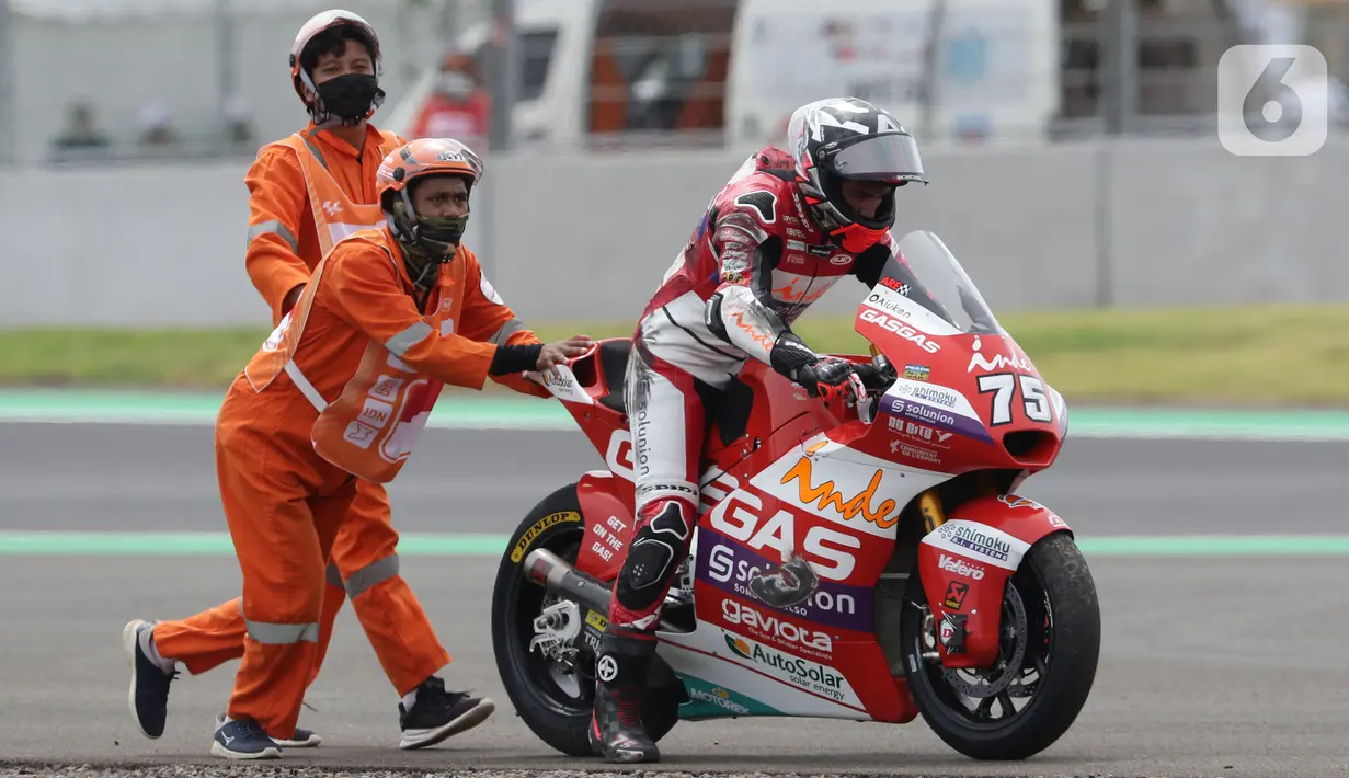 Marshal mendorong motor pembalap Albert Arenas yang keluar lintasan saat kualifikasi Moto2 di Pertamina Mandalika International Street Sirkuit, Lombok, NTB, Sabtu (19/3/2022). Marshal adalah petugas yang membantu di area lintasan saat terjadi insiden dalam balapan. (Liputan6.com/Helmi Fithriansyah)