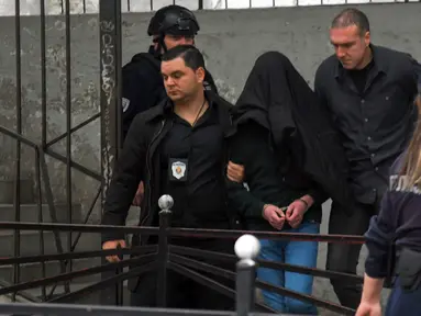 Seorang tersangka dikawal polisi di luar sekolah Vladislav Ribnikar di Beograd, Serbia, Rabu (3/5/2023). Seorang anak laki-laki berusia 13 tahun menembak mati delapan siswa dan seorang penjaga keamanan di sebuah sekolah di Beograd pada Rabu, 3 Mei 2023. (AP Photo)