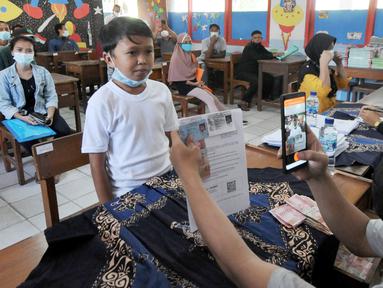 Petugas memotret warga penerima Bantuan Sosial Tunai (BST) di SDN Pondok Cabe Udik 03, Tangerang Selatan, Rabu (28/07/2021). Lebih dari dari 1800 warga mendapatkan BST yang dirapel dua bulan sekaligus dengan total Rp600ribu. (merdeka.com/Arie Basuki)