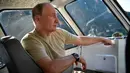 Dalam foto yang diambil pada  25 Agustus 2018, memperlihatkan Presiden Rusia Vladimir Putin duduk di dalam sebuah perahu di sungai Yenisey saat liburan singkatnya di Tuva daerah terpencil di Siberia selatan. (Alexei Nikolsky/Sputnik, Kremlin Pool via AP)
