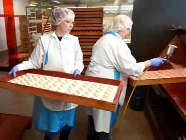 Pekerja memberi warna pada kue yang terbuat dari marzipan segar di tempat pembuatan tradisional JG Niederegger GmbH di Luebeck, Jerman (5/12). Marzipan adalah adonan yang bahan utamanya terbuat dari cacahan kacang almond dan gula. (AFP Photo/Stollarz)