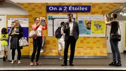 Calon penumpang mengambil gambar tanda bertuliskan "On a deux etoiles" di stasiun metro Etoile, Paris, Senin (16/7). Enam stasiun utama di Paris untuk sementara diganti namanya guna menghormati Prancis yang menjadi juara Piala Dunia. (AFP/Thomas SAMSON)