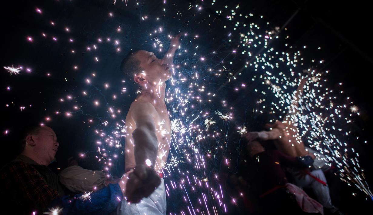 Sejumlah pria bermandinkan percikan kembang api saat mengikuti ritual eating flowers di provinsi Fujians, China (16/2). Ritual unik ini digelar untuk mengusir roh-roh jahat. (AFP/Johannes Eisele)
