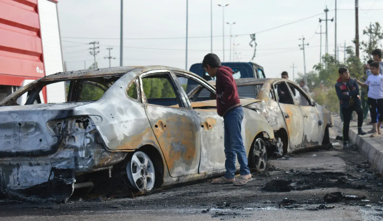 Seorang remaja melihat mobil yang hancur akibat bom di Ameriyat Falluja, Irak, Jumat (18/11). Mobil tersebut sengaja dijadikan bom yang diduga dilakukan oleh kelompok ISIS. (Reuters/Osamah Waheeb) 