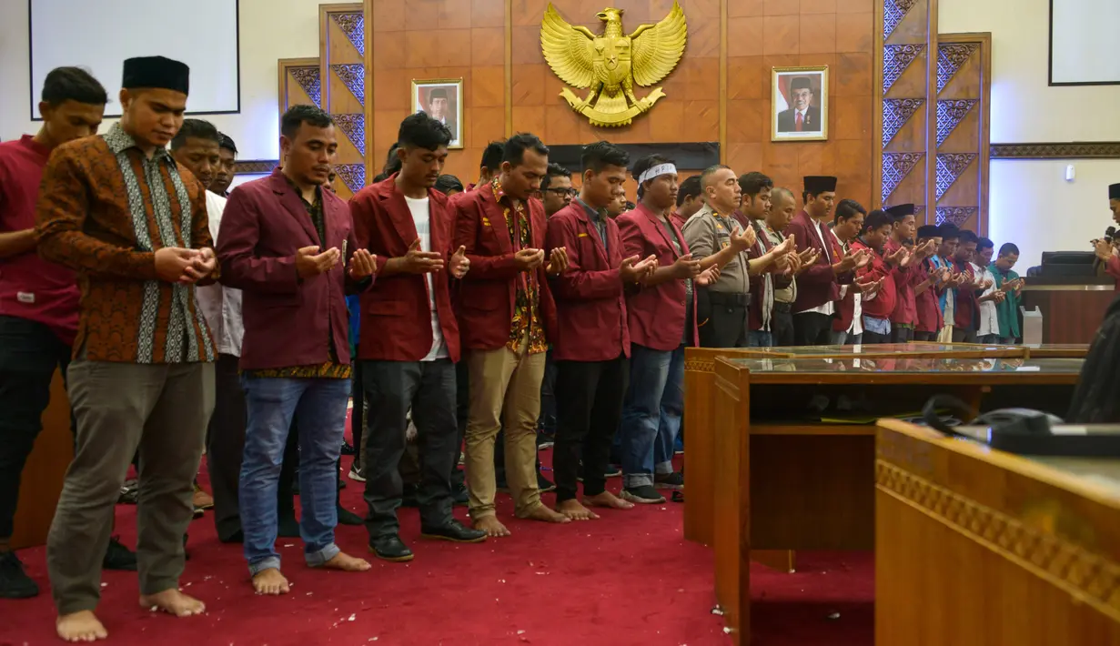 Mahasiswa dari berbagai perguruan tinggi dan anggota kepolisian melakukan doa bersama di Gedung Dewan Perwakilan Rakyat Aceh (DPRA), Jumat (27/9/2019). Doa dan salat gaib itu untuk 2 mahasiswa Universitas Halu Oleo Kendari yang tewas saat demo, Randi dan Yusuf. (CHAIDEER MAHYUDDIN/AFP)