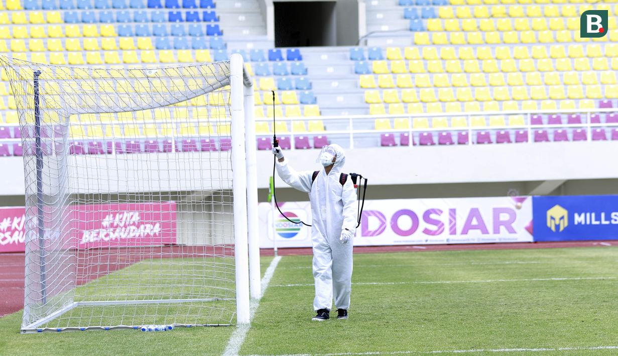 Petugas menyemprot jaring gawang dengan cairan disinfektan sebelum pertandingan antara Persikabo 1973 melawan Arema FC pada laga Piala Menpora di Stadion Manahan, Solo, Minggu (21/3/2021). (Bola.com/M Iqbal Ichsan)