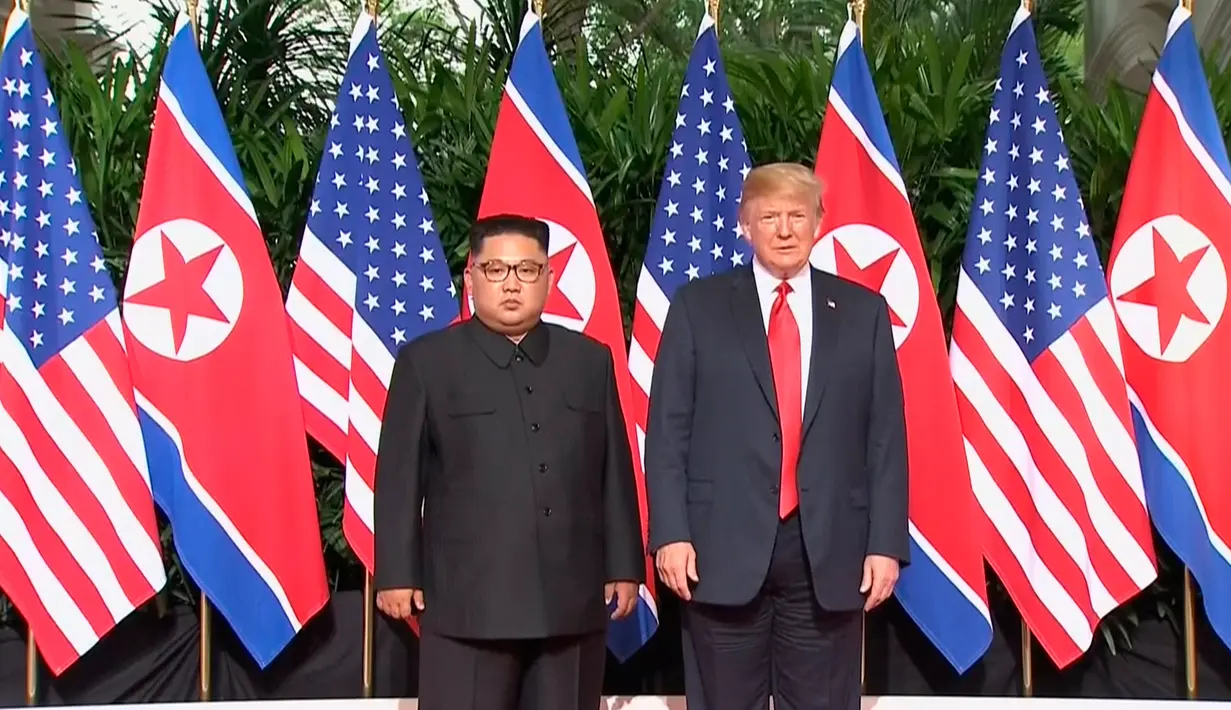 Presiden AS Donald Trump dan Pemimpin Korea Utara, Kim Jong-un berpose sebelum pertemuan mereka di resor Capella, Pulau Sentosa, Selasa (12/6). Pertemuan Trump  dan Kim sudah banyak dinantikan dunia. (Host Broadcaster Mediacorp Pte Ltd via AP)