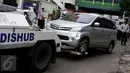 Petugas menderek kendaraan roda empat yang parkir sembarangan di kawasan Tanah Abang, Jakarta, Senin (14/11). Razia dilakukan menyusul maraknya parkir liar di kawasan Tanah Abang yang kerap menimbulkan kemacetan. (Liputan6.com/Gempur M Surya)