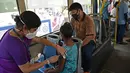 Seorang pekerja menerima suntikan vaksin Covid-19 Covishield di dalam bus penumpang yang diubah menjadi pusat vaksinasi keliling di Kolkata, Kamis (3/6/2021). India telah menderita pandemi yang menghancurkan sejak April, dan baru-baru ini mulai mereda. (Dibyangshu SARKAR/AFP)