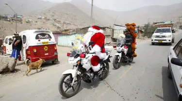 Seorang polisi Peru berpakaian seperti Santa Claus tiba dengan sepeda motornya selama perayaan Natal di Huaycan, Lima, Peru (15/12/2015). (REUTERS/Janine Costa)