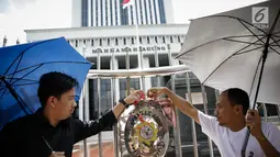 Massa saat menggelar aksi damai di depan Mahkamah Agung, Jakarta, Rabu (7/6). Dalam aksinya mereka menaburkan bungan pada payung sebagai bentuk simbol kekhawatiran matinya keadilan dan penegakan hukum. (Liputan6.com/Faizal Fanani)