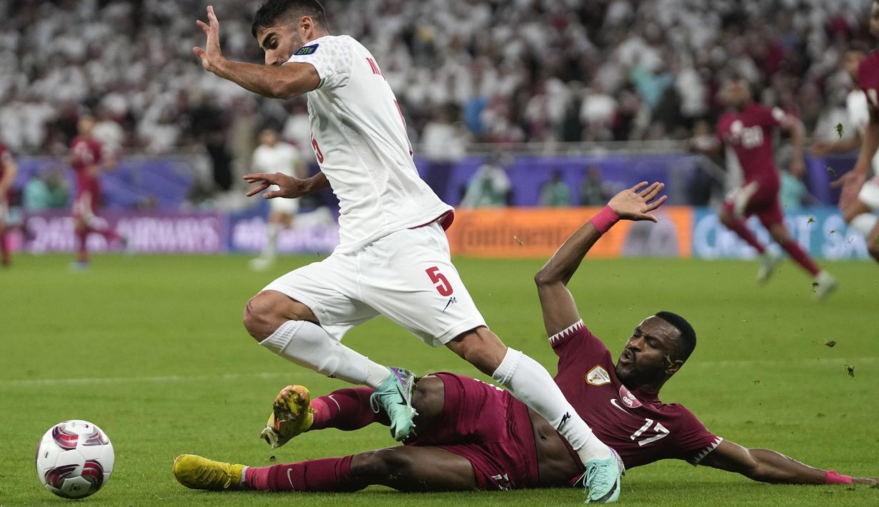 Pemain Qatar, Ismail Mohamad (bawah) berusaha merebut bola dari pemain Iran, Milas Mohammadikeshmarzi pada laga semifinal Piala Asia 2023 di Al Thumama Stadium, Doha, Qatar, Rabu (07/02/2024). (AP Photo/Thanassis Stavrakis)