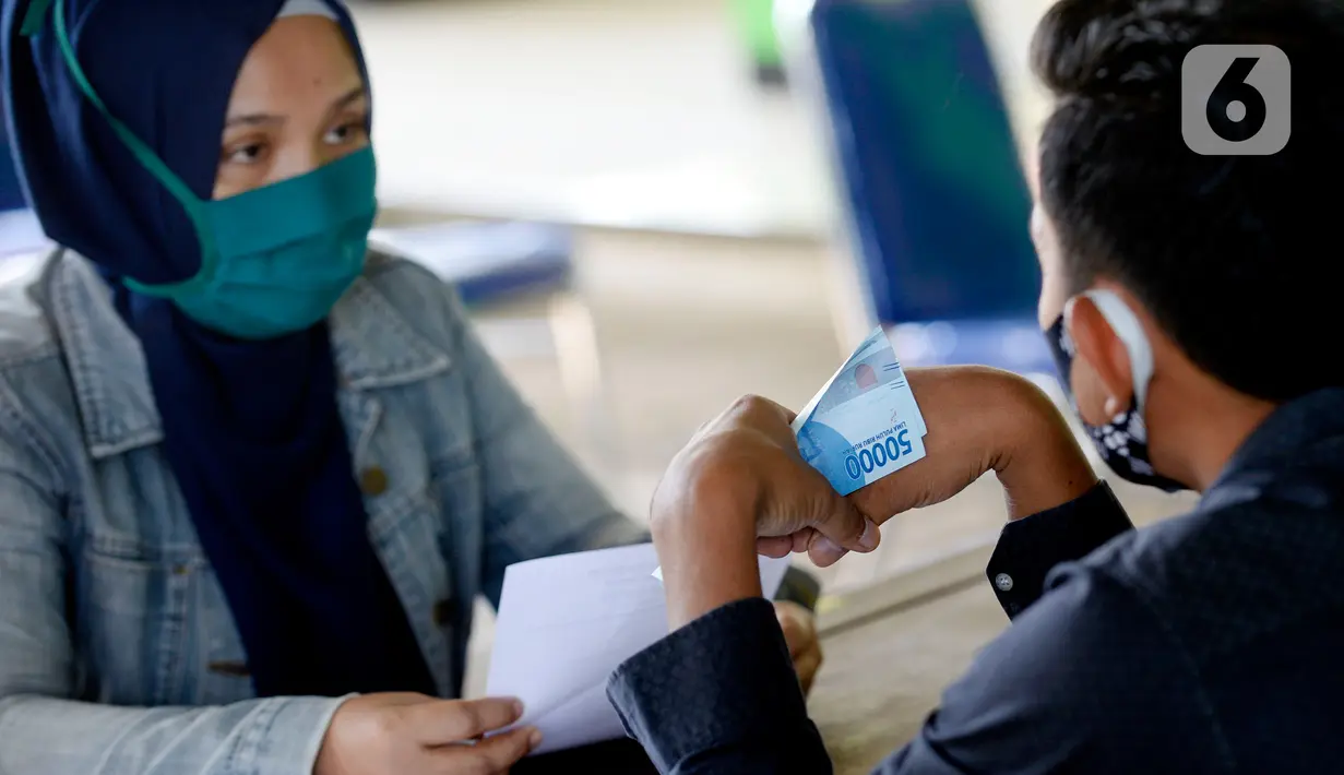 Petugas sedang menyerahkan Bantuan Langsung Tunai Dana Desa (BLT-DD) kepada warga Desa Curug di Kantor Desa Curug, Gunung Sindur, Kabupaten Bogor, Jawa Barat, Kamis (17/09/2020). Bantuan tersebut diberikan kepada 155 per KK untuk bisa mengurangi akibat terdampak COVID-19. (merdeka.com/Dwi Narwoko)