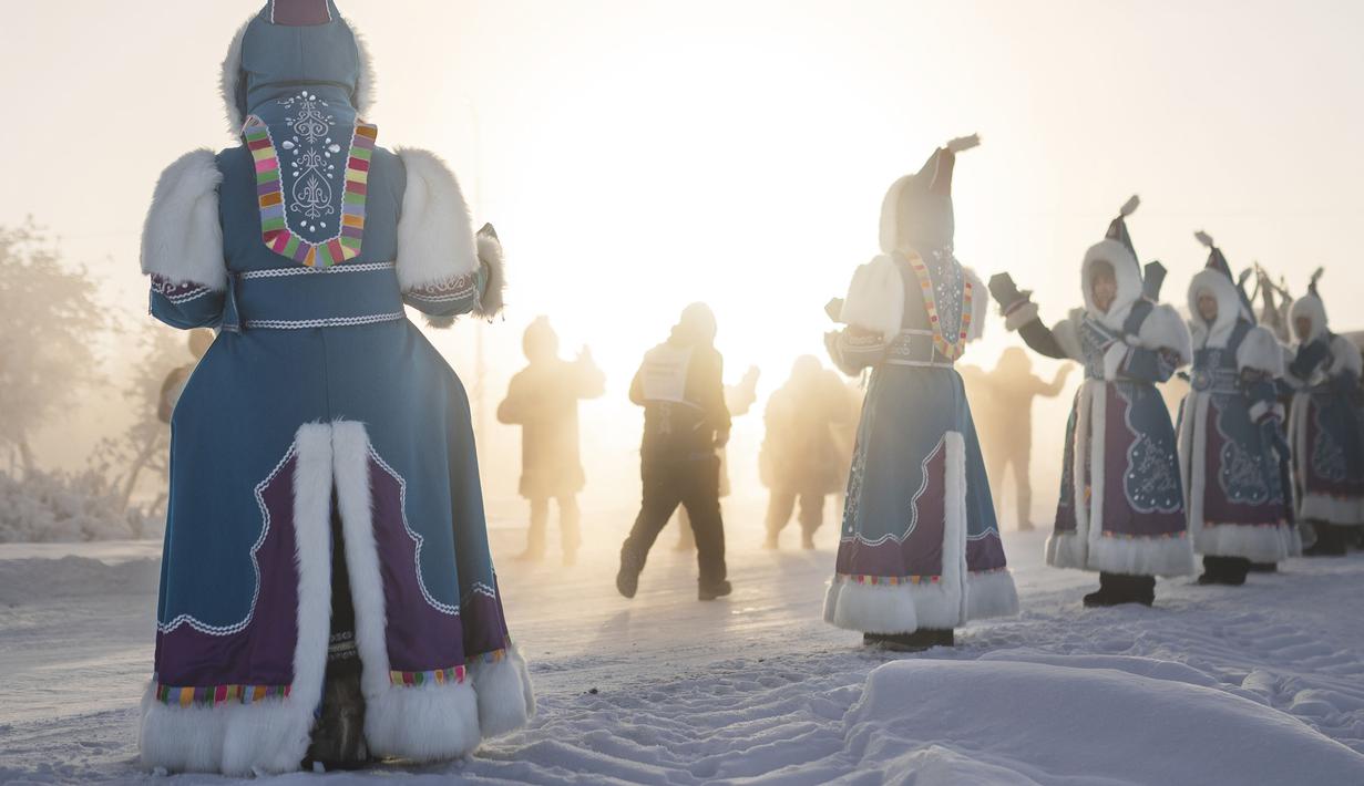 Wanita berkostum nasional Yakutian mendukung pelari yang sedang ambil bagian dalam maraton terdingin di dunia internasional pada suhu minus 53 derajat (-63,4 Fahrenheit) di dekat Oymyakon, republik Sakha, juga dikenal sebagai Yakutia, Timur Jauh Rusia, Sabtu, 22 Januari 2022. (AP/Ivan Nikiforov)