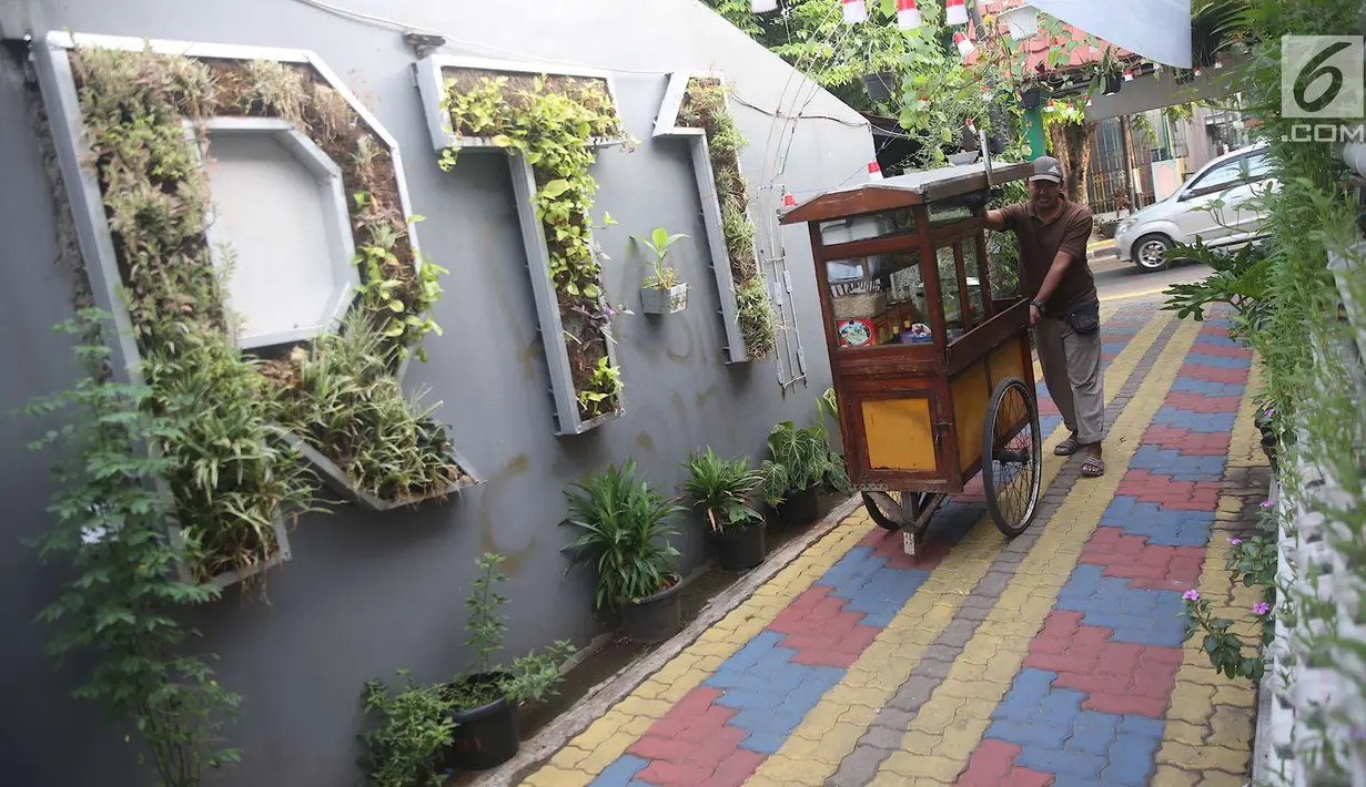 Pedagang melintas di salah satu gang kampung hijau di kawasan Malakasari, Jakarta, Sabtu (15/9). Tingginya kesadaran masyarakat akan pentingnya tumbuhan membuat kawasan tersebut terlihat asri dan dipenuhi berbagai tanaman. (Liputan6.com/Immanuel Antonius)