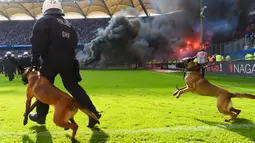 Petugas kepolisian berusaha menenangkan suporter yang mengamuk saat pertandingan antara Hamburg SV melawan VfL Borussia Moenchengladbach di Volksparkstadion, Sabtu (12/5/2018). Hamburg SV terdegradasi dari Bundesliga Jerman. (AP/Michael Sohn)