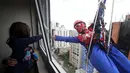 Petugas pembersih kaca berkostum Spiderman bercanda dengan seorang pasien anak yang dirawat di RS Infantil Sabara, Sao Paulo, Senin (10/10). Aksi ini bagian dari perayaan Hari Anak Brasil yang diperingati setiap 12 Oktober. (REUTERS/Paulo Whitaker)