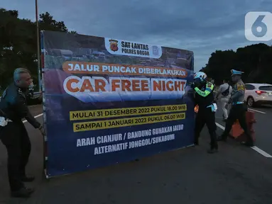 Petugas dari Polres Bogor memasang rambu penutupan jalan di pintu keluar Tol Gadog, Bogor, Sabtu (31/12/2022). Penutupan jalan jalur Puncak Bogor untuk gelaran Car Free Night dimulai sejak pukul 18.00 WIBdan dibuka kembali esok pagi pukul 06.00 WIB. (merdeka.com/Arie Basuki)