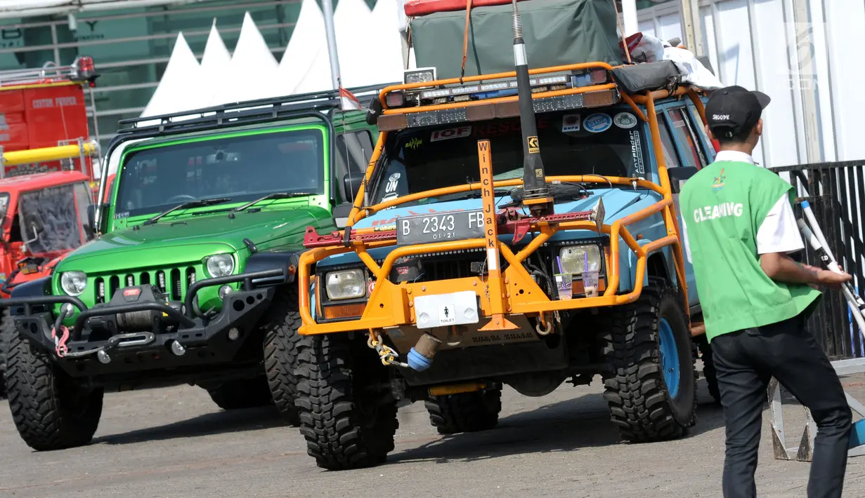 Pekerja melintasi deretan kendaraan off road yang dipamerkan pada Indonesia International Motor Show 2018 di JIExpo, Jakarta, Jumat (20/4). IIMS 2018 diselenggarakan hingga 29 April mendatang. (Liputan6.com/Helmi Fithriansyah)
