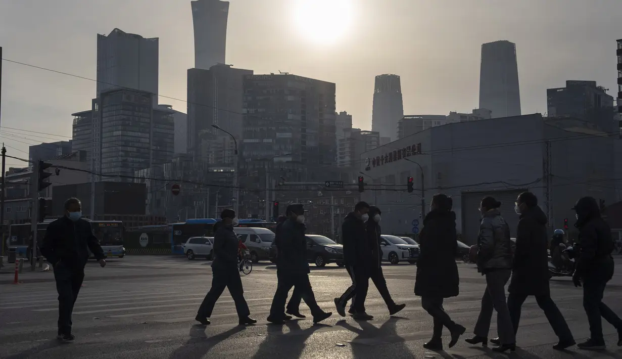Warga yang memakai masker melintasi persimpangan di Beijing, China, Jumat (2/12/2022). Lebih banyak kota melonggarkan pembatasan, memungkinkan pusat perbelanjaan, supermarket, dan bisnis lainnya dibuka kembali menyusul protes akhir pekan lalu di Shanghai dan daerah lain di mana beberapa orang menyerukan Presiden Xi Jinping untuk mengundurkan diri. (AP Photo/Ng Han Guan)