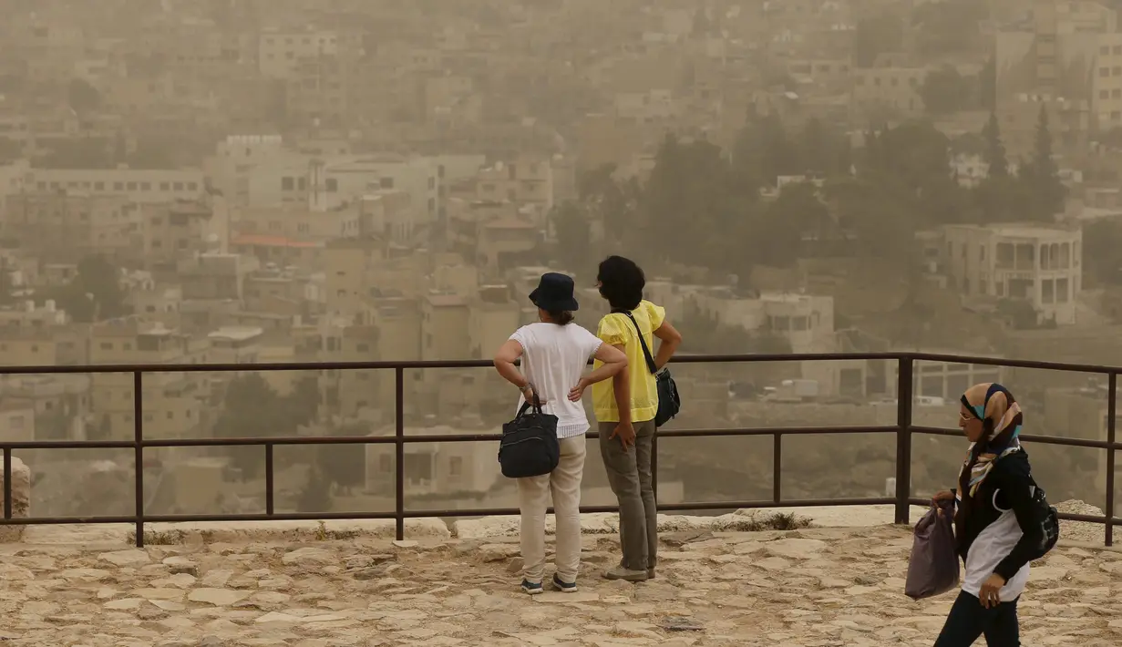 Wisatawan melihat pemandangan di Citadel Amman saat badai pasir berlangsung di kota Amman, Yordania, 8 September 2015. Badai pasir besar melanda Timur Tengah, menewaskan 2 orang dan ratusan orang dirawat di rumah sakit di Lebanon. (REUTERS/Muhammad Hamed)