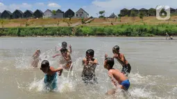 Anak-anak bermain pada aliran Sungai Cisadane di kawasan Keranggan, Setu, Tangerang Selatan, Banten, Minggu (20/3/2022). Cuaca panas terik dimanfaatkan mereka untuk berendam sambil bermain. (merdeka.com/Arie Basuki)