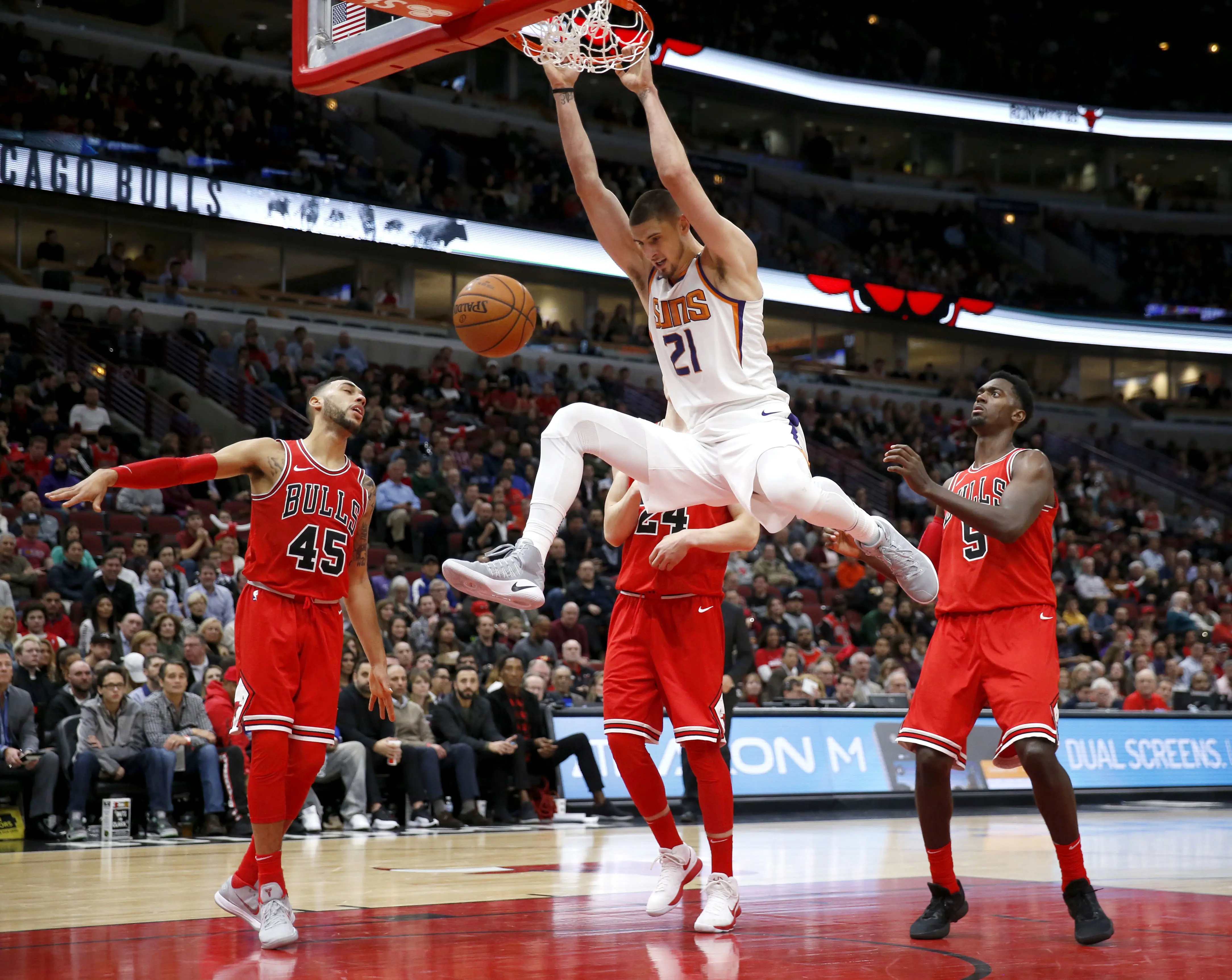 Center Phoenix Suns (tengah), Alex Len saat melakukan dunk ke jaring Chicago Bulls   (AP Photo/Charles Rex Arbogast)