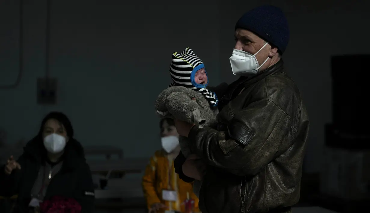 Seorang pengungsi dari Lviv, Ukraina, menggendong bayi setibanya di markas Palang Merah di Roma, Italia pada Selasa (22/3/2022). Konvoi kendaraan Palang Merah yang membawa 80 orang, sebagian besar orang tua dan sakit tiba pada Selasa di Roma. (AP Photo/Alessandra Tarantino)