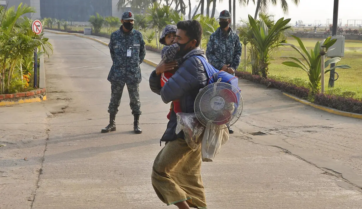 Seorang pengungsi Rohingya membawa seorang anak menuju kapal Angkatan Laut yang akan memindahkan mereka ke Pulau Bhasan Char di Chattogram, Bangladesh, Sabtu (30/1/2021). Bangladesh telah menepis kekhawatiran soal kemungkinan banjir di Pulau Bhasan Char. (AP Photo/Azim Aunon)