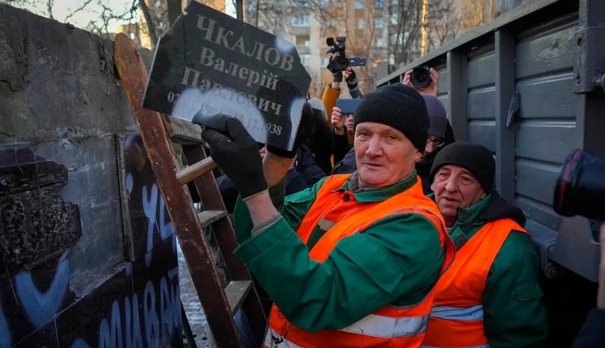 Seorang pekerja kota memegang plakat bertuliskan "Valery Chkalov" saat para pekerja membongkar monumen era Soviet untuk pilot Rusia di Kyiv, Ukraina, 8 Februari 2023. Ukraina mempercepat upaya untuk menghapus sisa-sisa pengaruh Soviet dan Rusia selama berabad-abad dari ruang publik dengan merobohkan monumen dan mengganti nama ratusan jalan untuk menghormati seniman, penyair, kepala militer, dan pemimpin kemerdekaan yang tumbuh di dalam negeri. (AP Photo/Efrem Lukatsky)