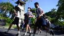 Anak-anak sekolah menggunakan tas mereka untuk melindungi diri saat latihan gempa dan tsunami di Tanjung Benoa, Kabupaten Badung, Bali, 24 Mei 2022. (SONY TUMBELAKA/AFP)