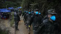 Tentara mengenakan masker wajah berbaris di jalan lereng bukit yang basah kuyup dekat lokasi kecelakaan pesawat Boeing 737-800 milik China Eastern Airlines untuk mencari kotak hitam kedua di desa Molang, di provinsi Guangxi, China barat daya, Rabu (24/3/2022). (AP Photo/Ng Han Guan)