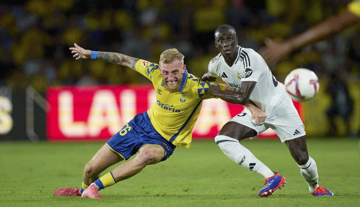 Pemain Real Madrid, Ferland Mendy, berebut bola dengan pemain Las Palmas, Oliver McBurnie, pada laga pekan ketiga La Liga 2024/2025 di Stadion Gran Canaria, Jumat (30/8/2024).  (AP Photo/Gabriel Jimenez)