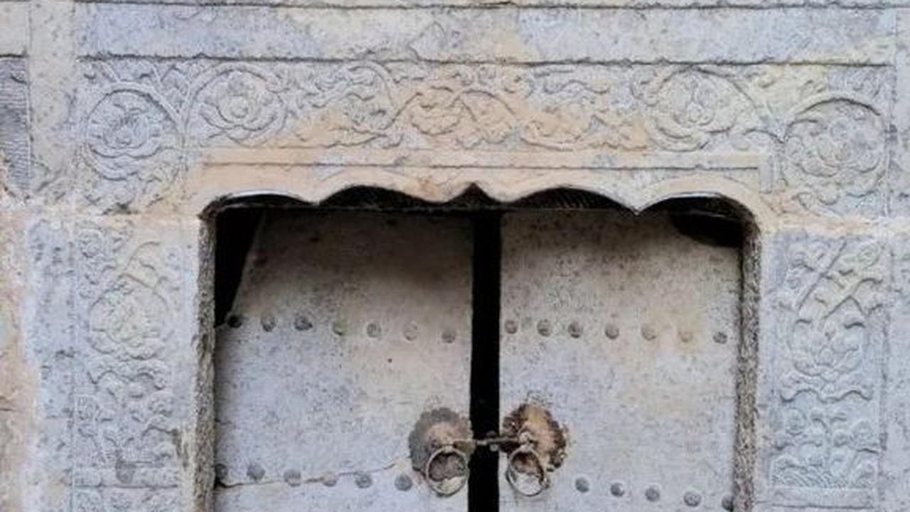 Sebuah gambar yang mencolok menunjukkan pintu masuk makam yang tersegel, dihiasi dengan gerbang batu dan satu set pintu ganda yang megah. Gerbangnya terbuat dari batu yang diukir meniru struktur kayu. Dua kepala naga menghadap ke luar di setiap ujung atap