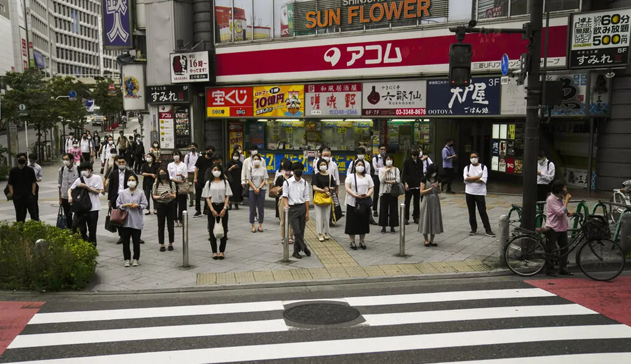 Komuter menunggu untuk menyeberang jalan menjelang Olimpiade 2020 di Tokyo, Jepang, Rabu (14/7/2021). Keadaan darurat akan berlaku sepanjang Olimpiade yang dibuka pada 23 Juli. (AP Photo/Jae C. Hong)