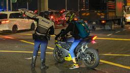 Polisi memandu pengendara sepeda motor saat antrean panjang kendaraan untuk memasuki Woodlands Checkpoint sebelum melintasi jalan lintas ke Malaysia di Singapura, Jumat (1/4/2022). Singapura dan Malaysia kembali membuka perbatasannya untuk semua pelancong yang divaksinasi lengkap.(Roslan RAHMAN/AFP)