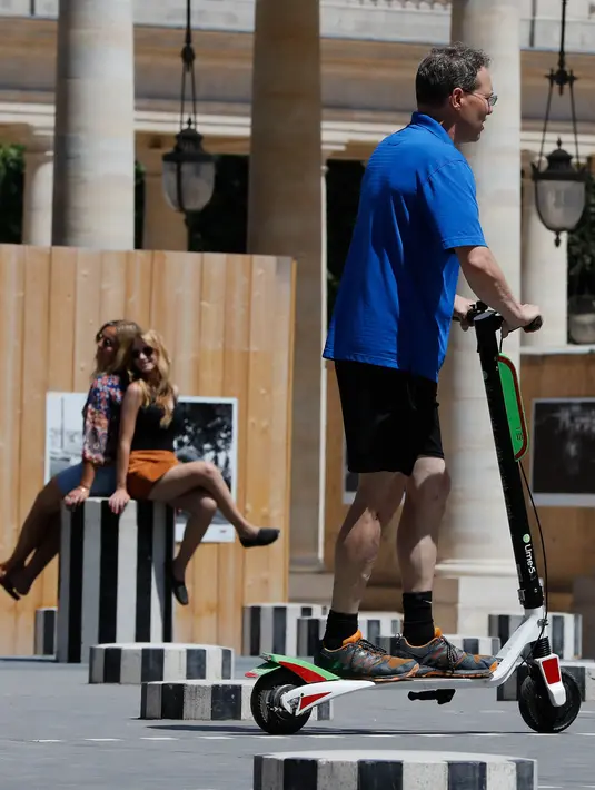 Seoarang pria menggunakan skuter listrik saat beraktivitas di Paris, Prancis (9/7). Skuter listrik ini dibuat oleh perusahaan AS Lime yang merupakan penyewaan transportasi sepeda dan skuter di berbagai kota. (AFP Photo/Francois Guillot)