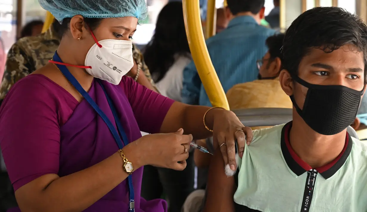 Seorang pekerja menerima suntikan vaksin Covid-19 Covishield di dalam bus penumpang yang diubah menjadi pusat vaksinasi keliling di Kolkata, Kamis (3/6/2021). India telah menderita pandemi yang menghancurkan sejak April, dan baru-baru ini mulai mereda. (Dibyangshu SARKAR/AFP)