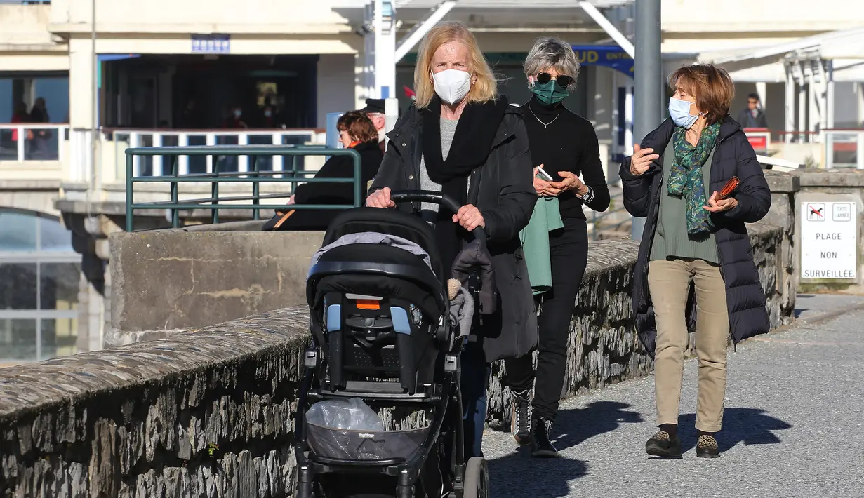 Orang-orang yang memakai masker berjalan-jalan di Saint-Jean-de-Luz barat daya Prancis, Rabu (2/2/2022). Selangkah demi selangkah, banyak negara melonggarkan pembatasan COVID-19 di tengah harapan gelombang omicron mungkin telah melewati puncaknya. (AP Photo/Bob Edme)
