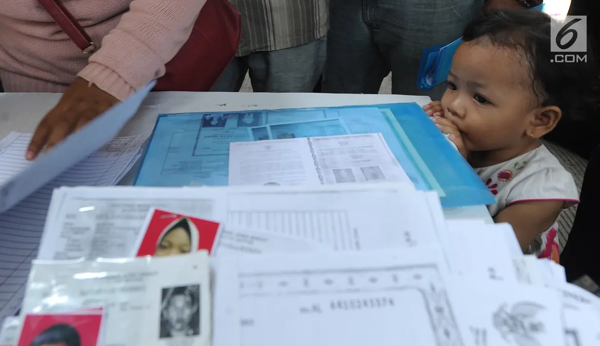 Seorang anak menyaksikan pembuatan Kartu Identitas Anak (KIA) yang digelar Disdukcapik Kota Depok di Kantor Kecamatan Cinere, Depok, Jawa barat, Rabu (2/10/2019). Ratusan emak-emak menyerbu pelayanan gratis ini sebagai syarat administrasi anak masuk tahun ajaran baru. (merdeka.com/Arie Basuki)